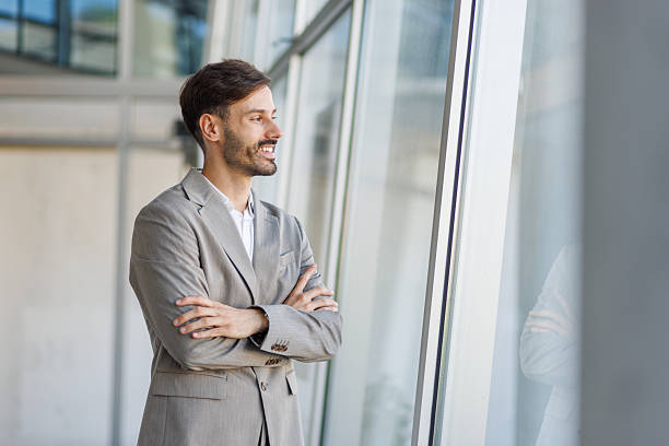 istock Businessman smiling and looking out the window in office building 2235956738