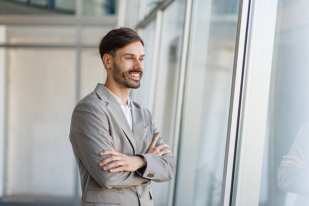 istock Smiling businessman looking out large office window 2235956757