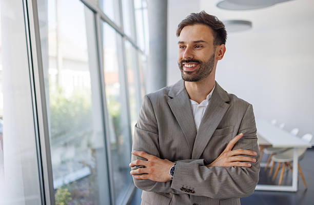 istock Young businessman smiling and looking outside in modern office 2235957289
