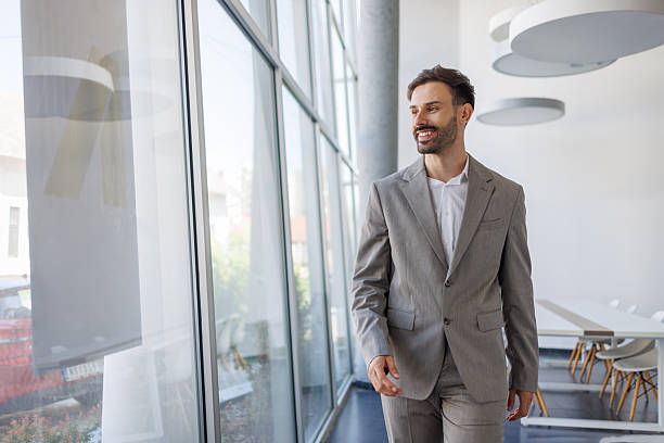 istock Businessman walking in modern office by the window 2235957302