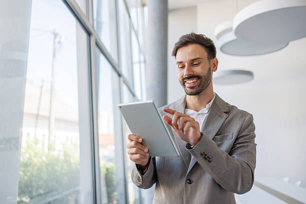 istock Smiling businessman using digital tablet in modern office 2235957326