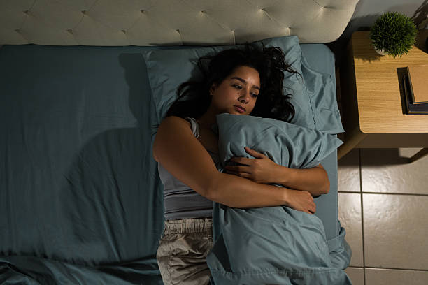 istock Upset Latina hugging pillow lying in bed after breakup 2235957492