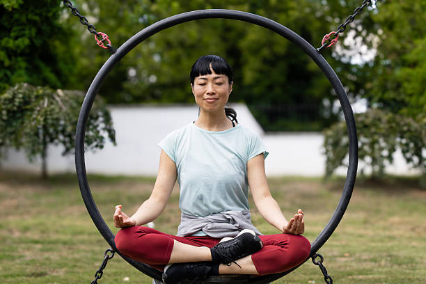istock Young woman meditating in a swing in a park 2235957512