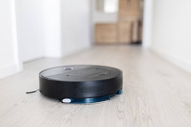 istock Robotic vacuum cleaner moving through hallway on wooden floor 2235958245