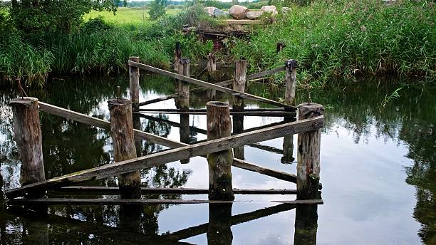 istock Neglected Destroyed Damaged Wooden Bridge over Countryside River 2235965364