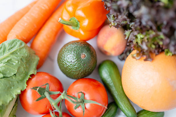A vibrant assortment of fresh vegetables and fruits including carrots, tomatoes, avocados, and greens, emphasizing health and vitality.