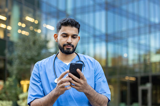istock A doctor in scrubs using a phone outside a modern building. 2235972404