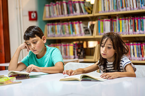 Kid child girl students group together happy smile talking look reading book enjoy in school public library. Learning education knowledge development on storytelling funny fantasy stories at school