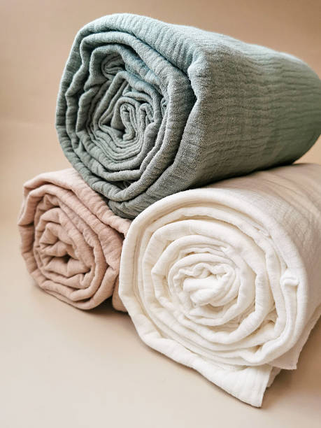 istock Soft muslin blankets in pastel colors rolled and stacked with eucalyptus leaves 2235973206