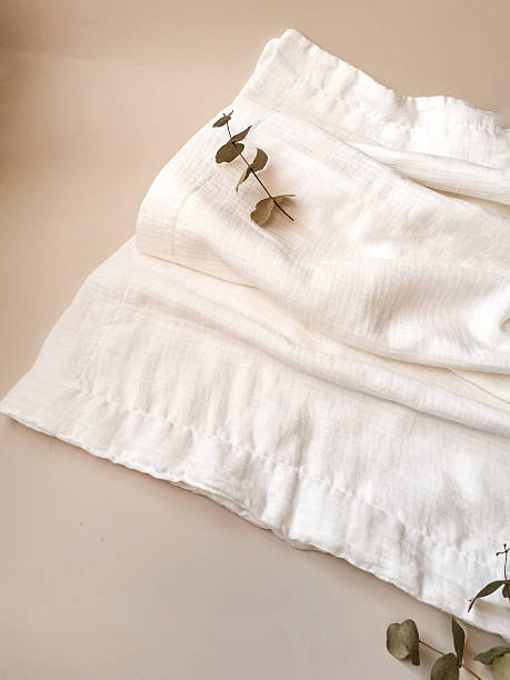 istock Soft muslin blankets in pastel colors rolled and stacked with eucalyptus leaves 2235973259