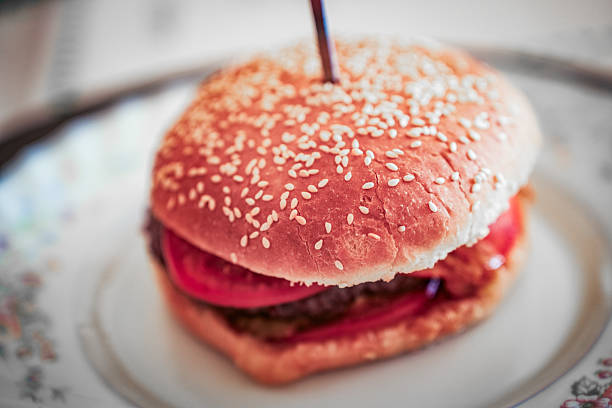 Photo of a homemade hamburger placed on a white surface. A juicy and layered sandwich with fresh ingredients, ideal for culinary branding or editorial use