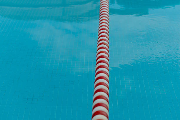 A swimming pool lane line stretches vertically through the blue water. Reflections visible in the water create a rippled, textured effect.