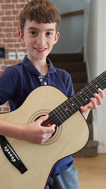 istock Smiling young boy playing an acoustic guitar 2235983090