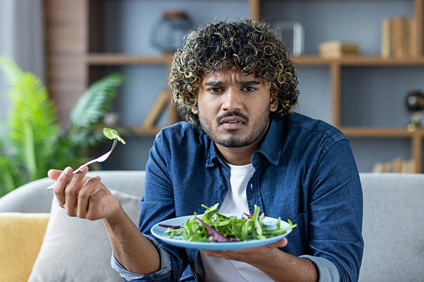 istock Confused man holding a salad plate and expressing uncertainty while dining 2235983625