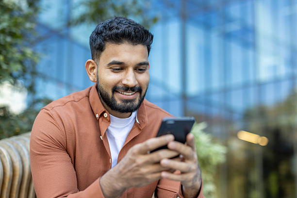 istock A handsome man is smiling while looking at his phone outdoors. 2235986805