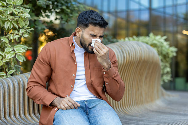 istock A man is seen blowing his nose outdoors, possibly experiencing cold or allergy symptoms during the day. 2235986874
