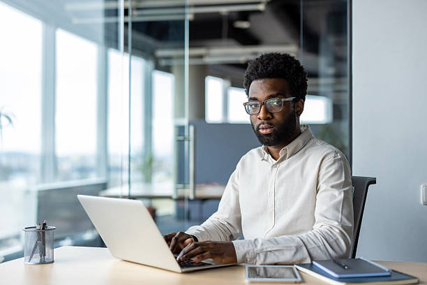 istock A man in a modern office using a laptop, looking focused and confident. 2235987350
