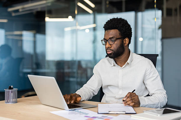 istock Focused businessman working on laptop with documents in a modern office 2235987414
