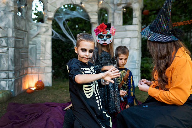 istock Halloween witch helping children with face and body art. 2235987422