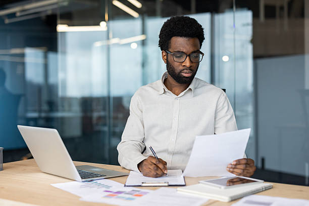 istock A focused businessman reviews documents at his desk in a modern office setting. 2235987432