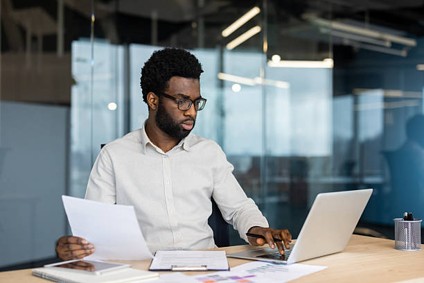 istock Focused businessman analyzing documents and working on his laptop in the office. 2235987479