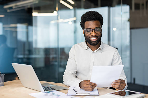 istock Smiling businessman reviewing documents at desk in modern office setting 2235987487