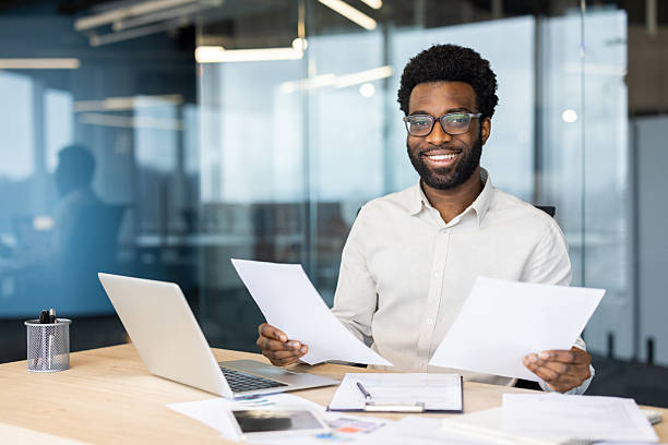 istock Confident businessman working on documents and smiling in a modern office setting 2235987494