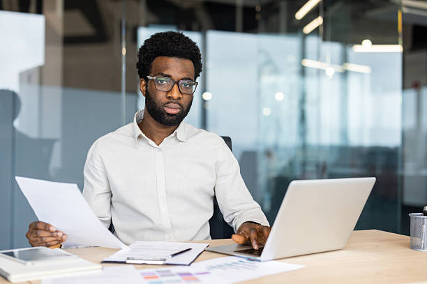 istock Professional man working at desk with laptop and documents in modern office 2235987495