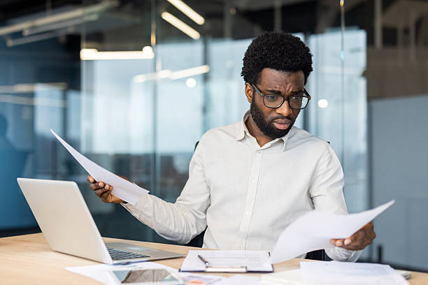 istock Confused businessman reading documents at office desk 2235987506