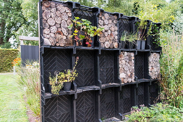 A number of black plastic crates is reused to build a so called insect hotel filled with tree stumps and firewood with small holes to serve as shelter for insects.