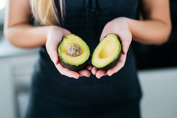 istock Woman holding a halved avocado in hands 2235997377