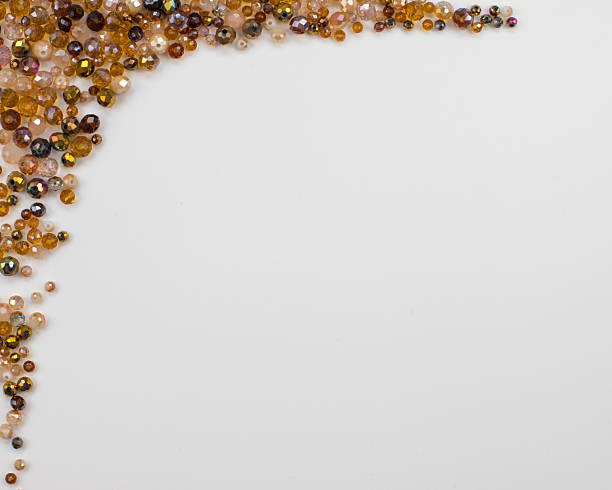 On a white background brown glass crystal beads of various sizes, both matte and transparent, form a decorative frame along the left and top sides, including the top left corner. Center and right side provide ample copy space. Perfect for jewelry, craft, DIY, decoration, advertising, marketing, and banners. High quality photo