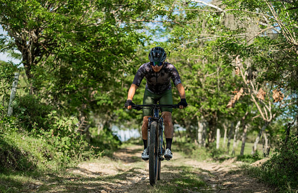 istock Mountain biker riding along a rural trail surrounded by green trees 2235999509