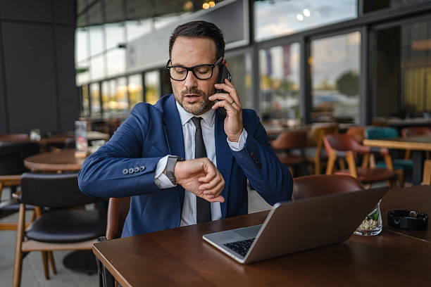 istock Businessman waiting for someone while talking on phone and checking time 2236000817