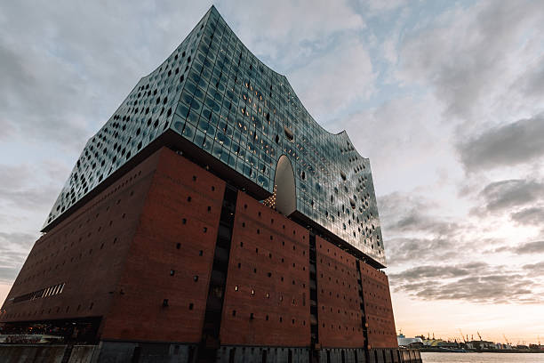 Hamburg, Germany, Europe - September 14, 2023: The Elbphilharmonie, Hamburg’s architectural masterpiece, rises above the harbor with its iconic glass structure. The modern concert hall, completed in 2017, combines cutting-edge design with the historic base of a former warehouse. It has become the symbol of Hamburg’s skyline and a major European cultural landmark