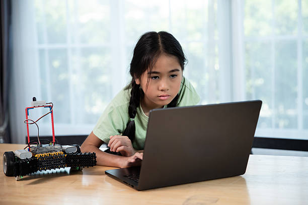 istock An Asian girl focuses intently while using a laptop to program a robot car during a STEM activity. She is learning about coding and robotics through hands-on experience, representing modern education and future-ready skills 2236003681