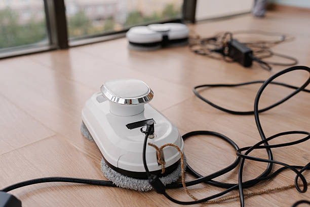 istock Modern robot window cleaner charging on floor by dirty large window, preparing for automatic cleaning of high-rise building windows with advanced technology 2236005407