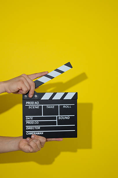 istock Hands holding a movie clapperboard on a yellow background 2236007233