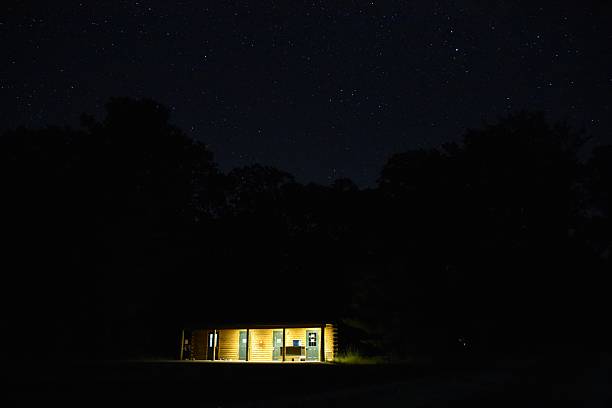 istock nighttime shot of a cabin lit up by a light from a window 2236010265