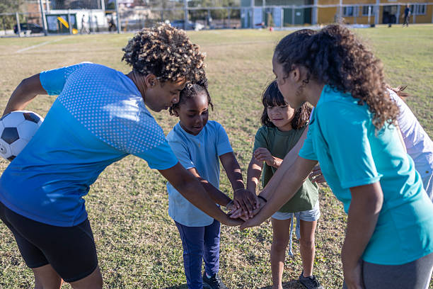 Happy football children relax on field sports portrait for group collaboration, teamwork and motivation. Soccer girl kids face lying on ground together for training support, love and commitment above