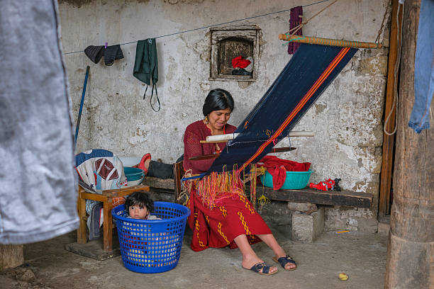 San Cristobal de las Casas, Mexico - February 11, 2022: Three women in Mayan clothes  sitting on the bench and selling traditional Mexican souvenirs
