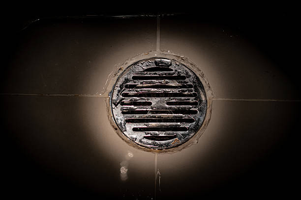 the flashlight light shines on the floor with a grille on the drain hole