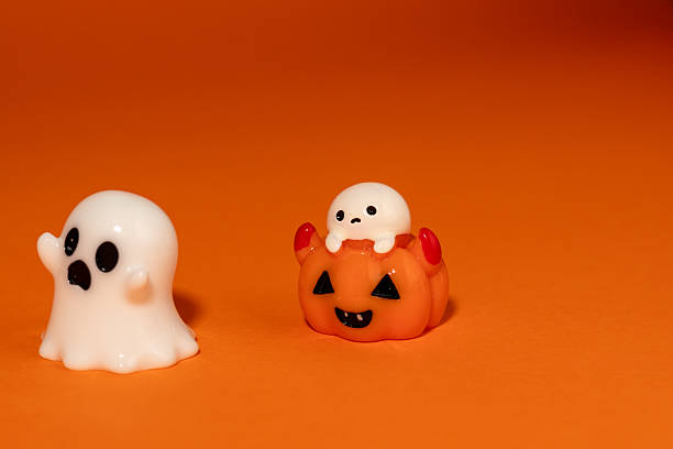 istock frightened ghost figurine reacting to a small ghost popping out of a pumpkin. The tiny ghost inside the jack-o'-lantern scares the larger ghost, making it scream and appear to run away. 2236015799