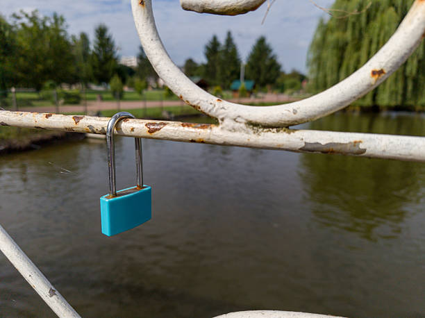 istock A blue padlock attached to a metal fence by a river 2236019136