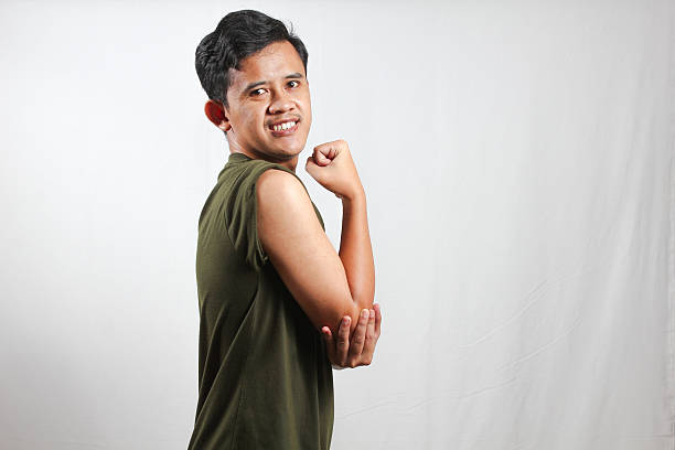Excited young Asian man showing arm muscles isolated on white background
