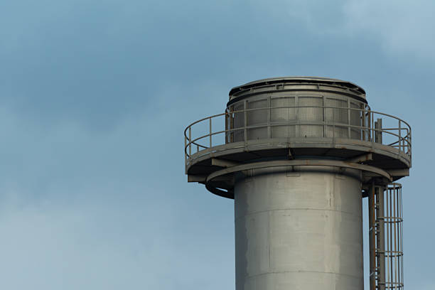 Stock image showcasing towering chimneys of a power plant with interconnected pipelines below, captured  under a cloudy sky. The composition highlights the scale of industrial infrastructure and its significance in energy production. Perfect for illustrating topics related to heavy industry, energy generation, environmental issues, and industrial development in modern cities. Suitable for editorial, commercial, and educational use.
