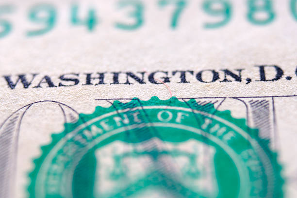 A detailed close-up image of the engraved text Washington, D.C. on a one dollar bill, showcasing the texture and design of U.S. currency.