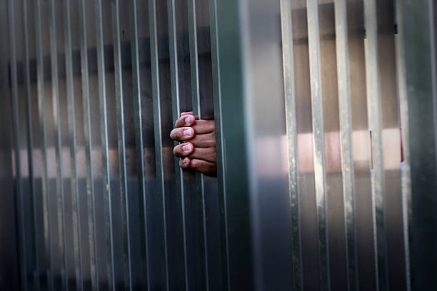 istock Hands Reaching Through Metal Bars in a Captive Environment 2236026054