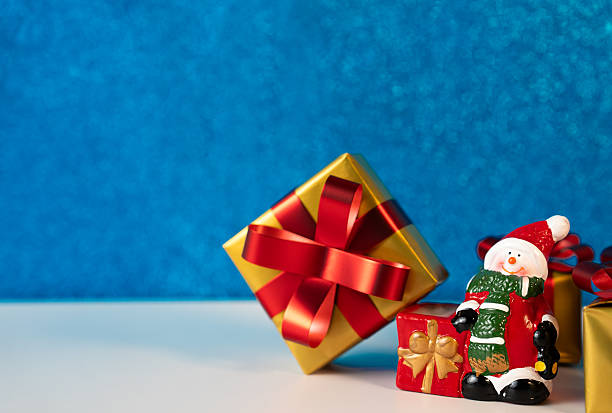 Holiday present with ribbon and Santa figurine on blue background. Ideal for Christmas cards and festive designs.