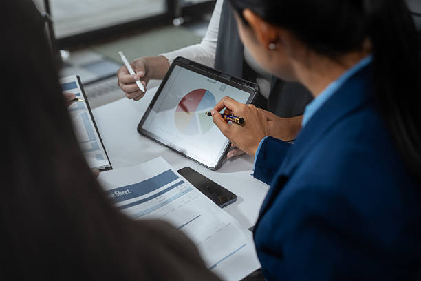 Entrepreneurs, marketers, managers, and financial analysts gather around the table to analyze data, present results, plan strategies, discuss efficiencies,grow their businesses through collaboration